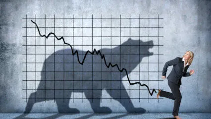 Mujer de negocios huye de una sombra en forma de oso que representa una caída del mercado bajista de criptomonedas.