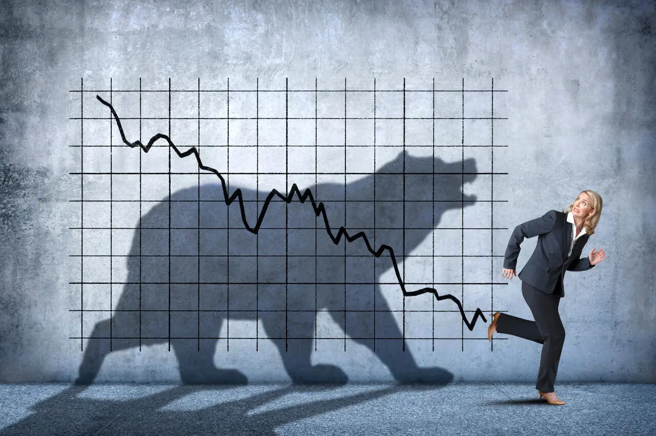 Mujer de negocios huye de una sombra en forma de oso que representa una caída del mercado bajista de criptomonedas.