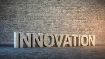 Representación 3D de la palabra INNOVACIÓN en piedra sobre una pared de ladrillo. Concepto de innovación abierta.
