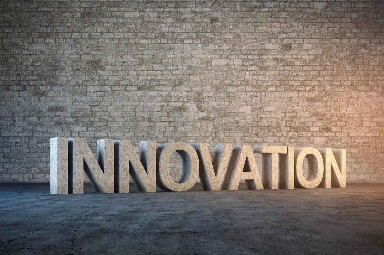 Representación 3D de la palabra INNOVACIÓN en piedra sobre una pared de ladrillo. Concepto de innovación abierta.