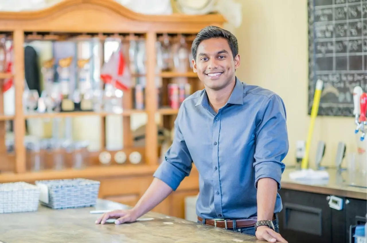 Feliz joven empresario de pie junto a un mostrador de bar
