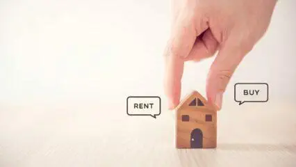 Mano colocando una maqueta de casa entre los bocadillos de 