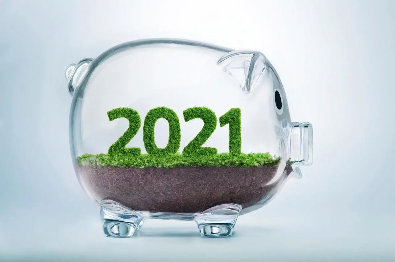 Alcancía de cristal con el año 2021 en hierba. Invirtiendo en el futuro.