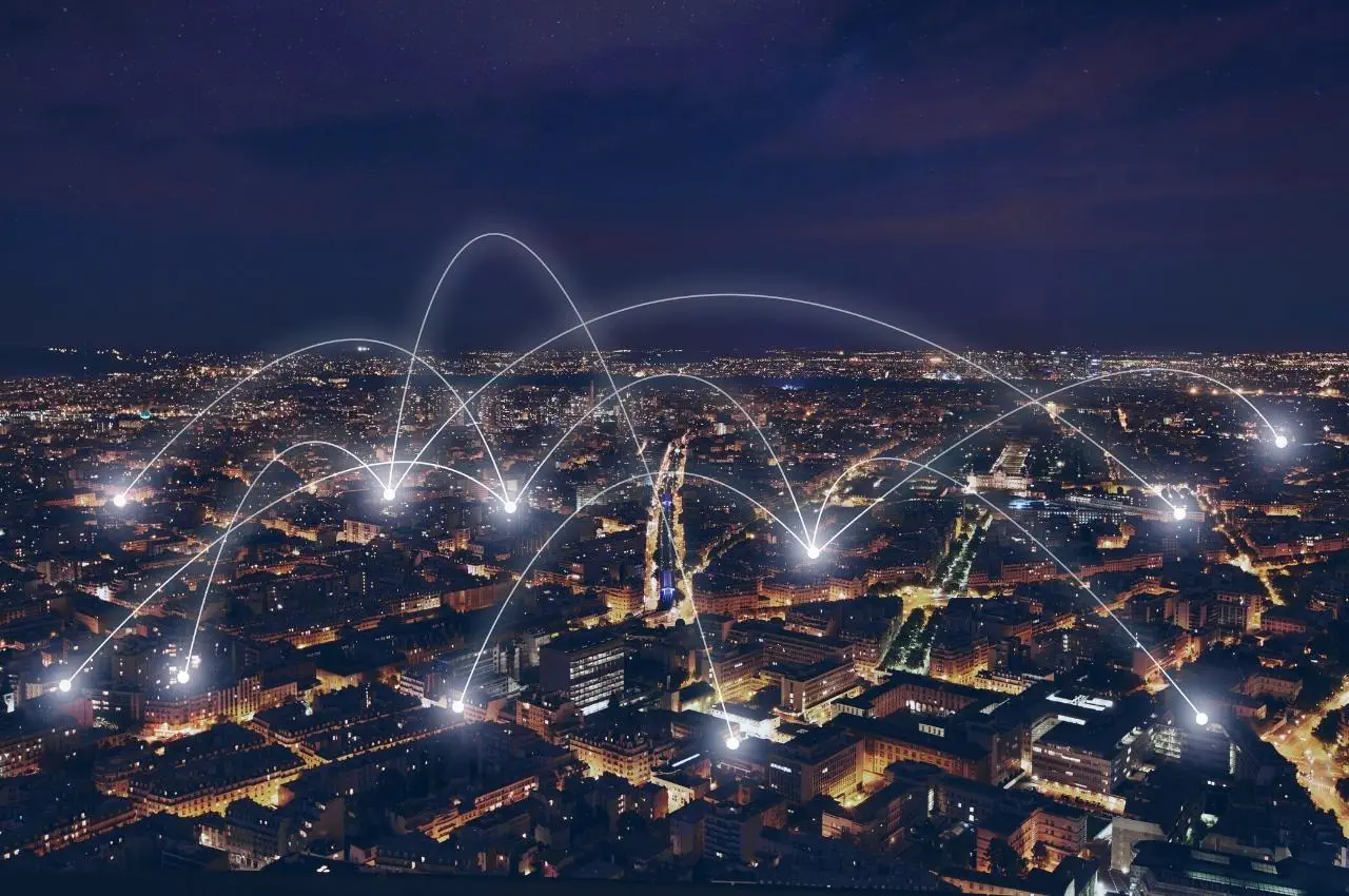 Horizonte de una ciudad nocturna con conexiones de red brillantes que ilustran un ecosistema empresarial.