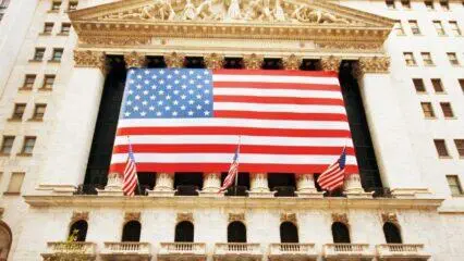 Edificio de la Bolsa de Valores de Nueva York con una gran bandera estadounidense. Invertir en el mercado bursátil estadounidense.