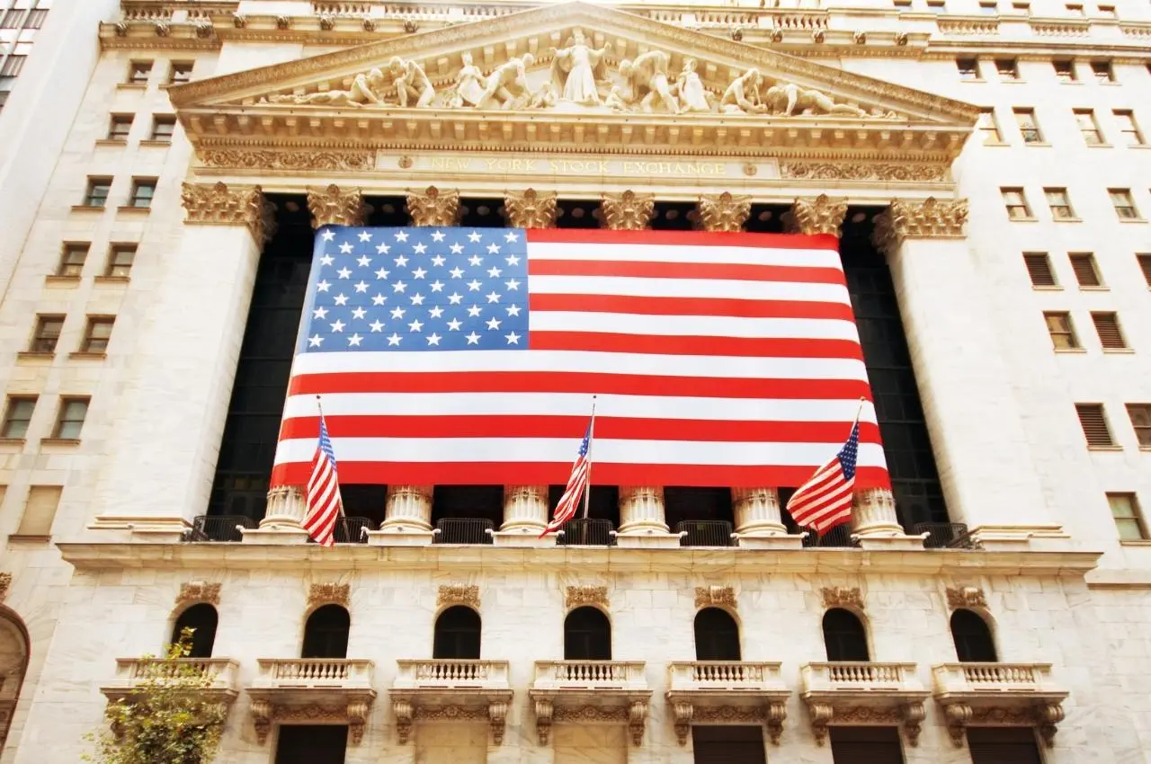 Edificio de la Bolsa de Valores de Nueva York con una gran bandera estadounidense. Invertir en el mercado bursátil estadounidense.