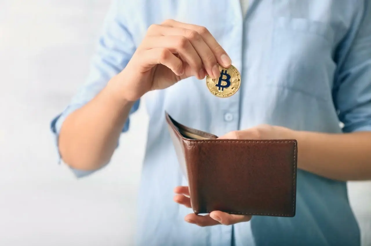 Mujer colocando bitcoins en una billetera de cuero