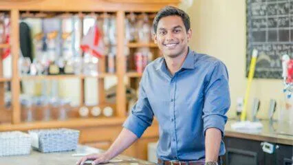 Feliz joven empresario de pie junto a un mostrador de bar