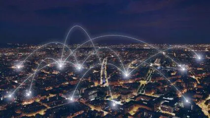 Horizonte de una ciudad nocturna con conexiones de red brillantes que ilustran un ecosistema empresarial.