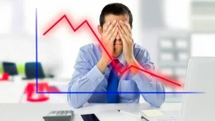 Empresario estresado cubriéndose los ojos con un gráfico de tendencia bajista superpuesto. ¡Evita estos errores comunes en el mercado de valores!