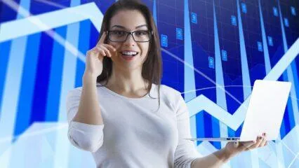 Mujer sonriente con laptop, gráficos de bolsa de valores. Consejos inversión Bolsa de Lima.