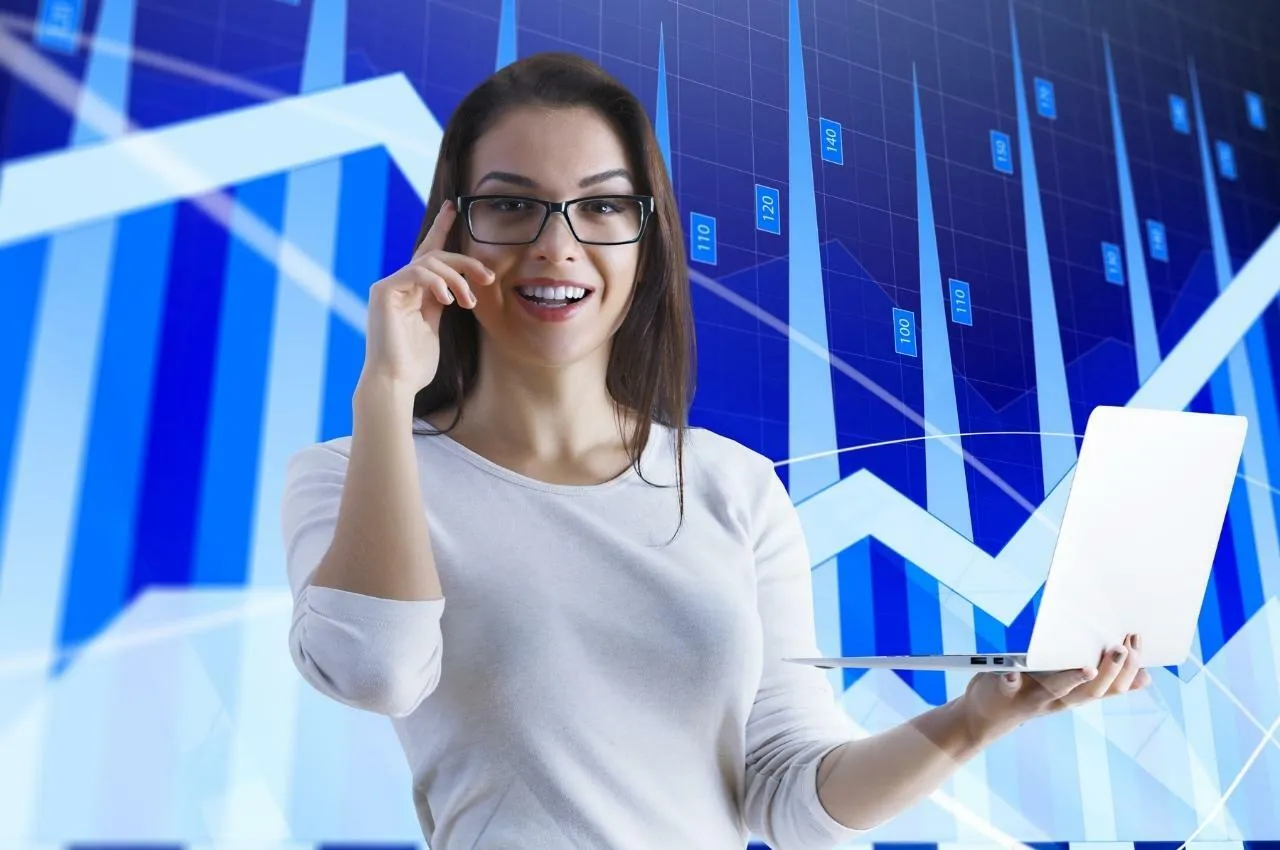 Mujer sonriente con laptop, gráficos de bolsa de valores. Consejos inversión Bolsa de Lima.