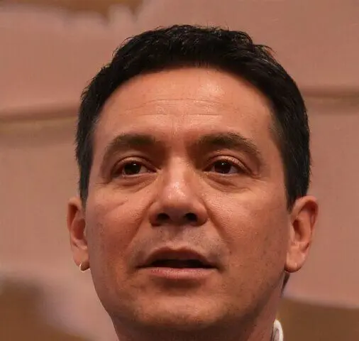 Retrato en primer plano de un hombre con cabello oscuro y ojos marrones.