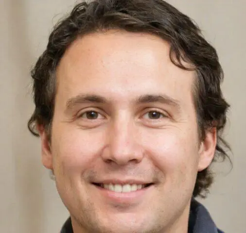 Foto de rostro de un hombre con cabello castaño y una sonrisa amistosa.
