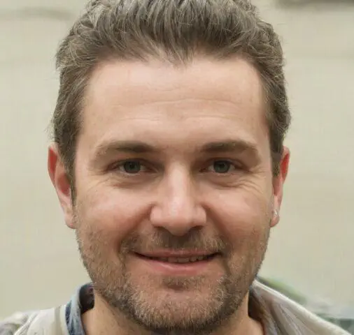 Retrato en primer plano de un hombre con cabello castaño corto y barba, sonriendo.