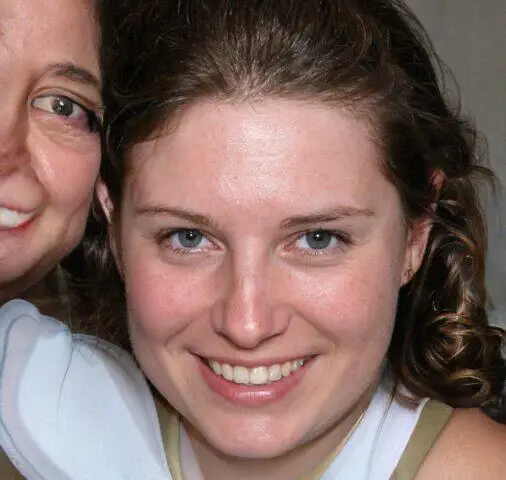Primer plano de dos mujeres, una de ellas sonriendo ampliamente. Amistad, felicidad.