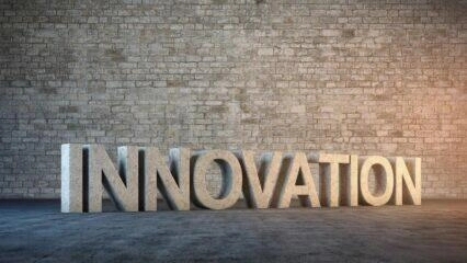 Representación 3D de la palabra INNOVACIÓN en piedra sobre una pared de ladrillo. Concepto de innovación abierta.