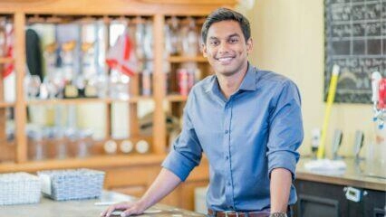 Feliz joven empresario de pie junto a un mostrador de bar