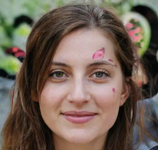Retrato de primer plano de una mujer joven con pétalos de flores rosas en la cara.