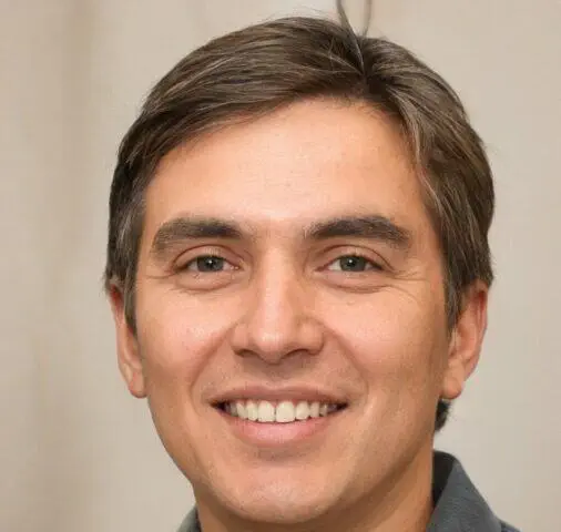 Foto de rostro de un hombre con cabello castaño corto y una sonrisa amistosa.