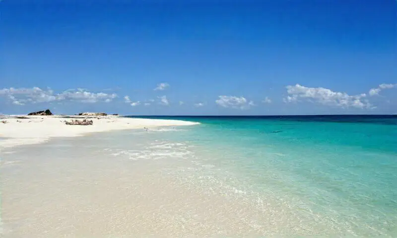 Impresionantes aguas turquesas bañan una playa de arena blanca prístina.