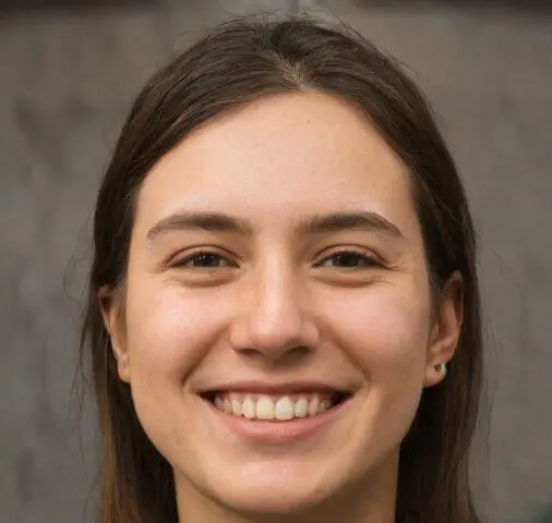 Retrato de una mujer joven sonriendo, con cabello castaño y piel clara, frente a un fondo gris neutro.