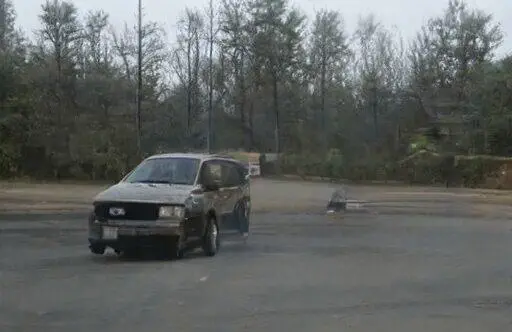 Una minivan haciendo un burnout en un estacionamiento vacío.